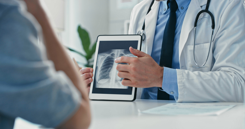 Doctor reviewing lung X-ray with patient, illustrating evaluation of mesothelioma symptoms