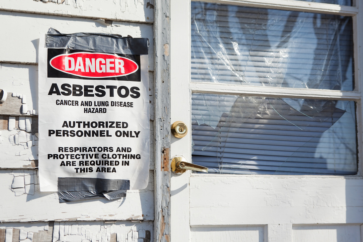 Warning sign for asbestos hazard on home entry door, highlighting secondhand asbestos exposure risk