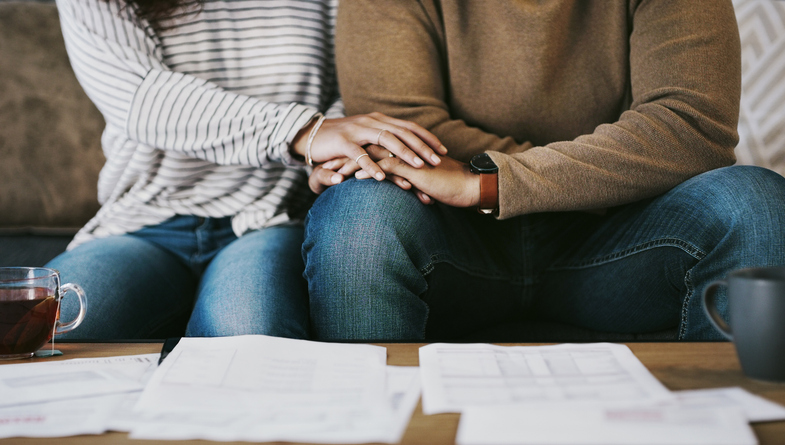 Couple holding hands while reviewing medical bills and paperwork, reflecting mesothelioma support and caregiver stress