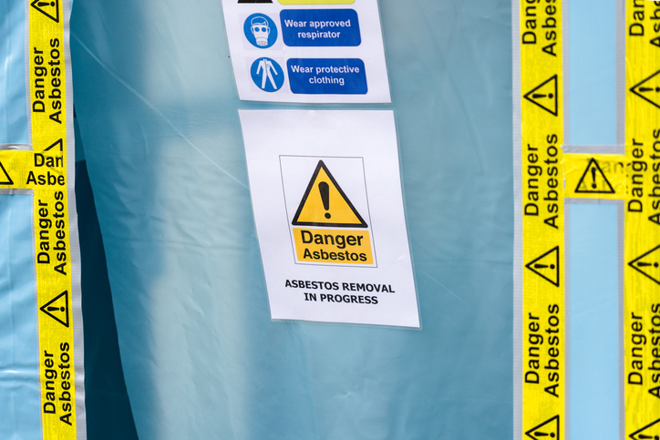 Danger asbestos sign and warning tape at a removal site, illustrating global health risks and safety efforts in Indonesia and Australia