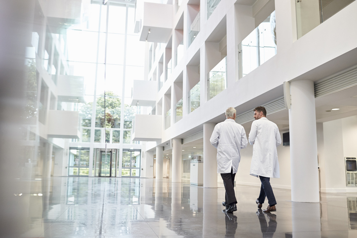 Two doctors walking through a modern hospital atrium, representing mesothelioma specialists