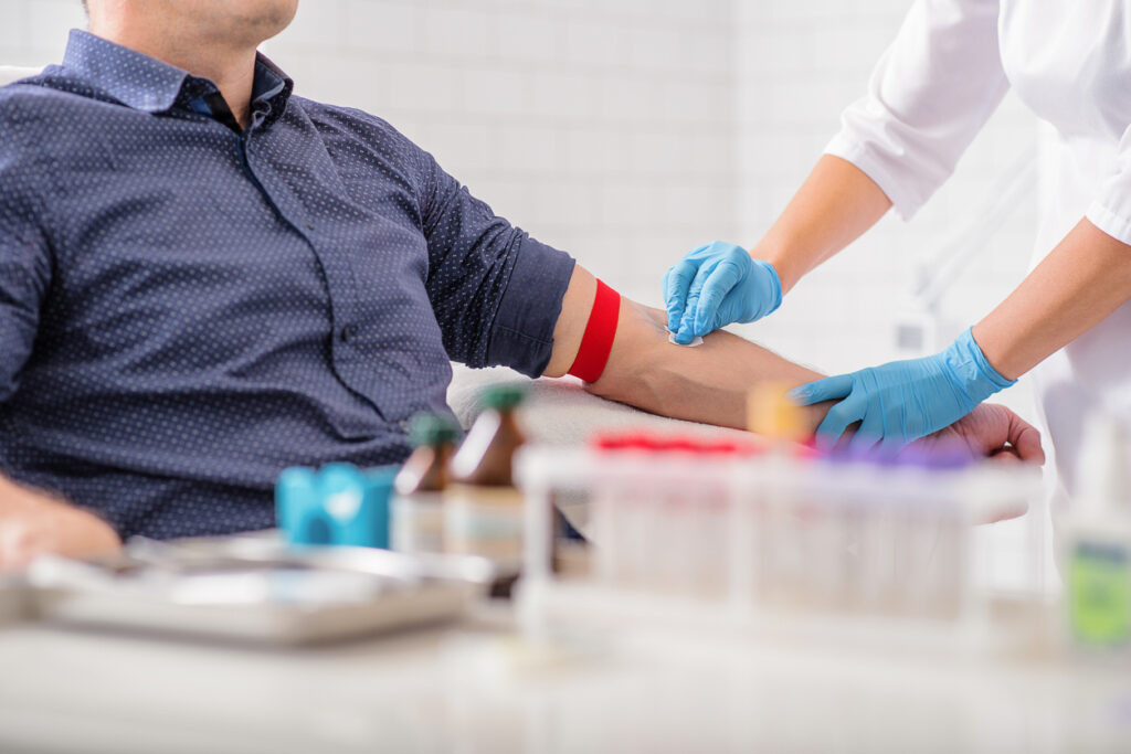 Healthcare professional preparing a patient’s arm for a blood draw as part of a mesothelioma clinical trial screening process.