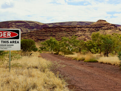 Danger asbestos warning sign at an outdoor mine site with rocky landscape in the background
