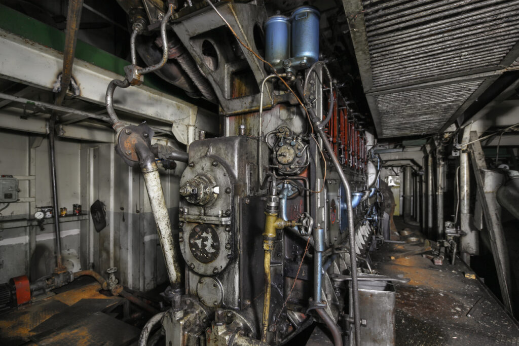Vintage ship engine room with dense piping, valves, and machinery where asbestos insulation was widely used