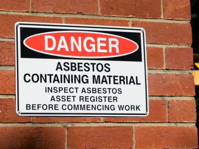 Danger asbestos containing material warning sign mounted on a brick wall