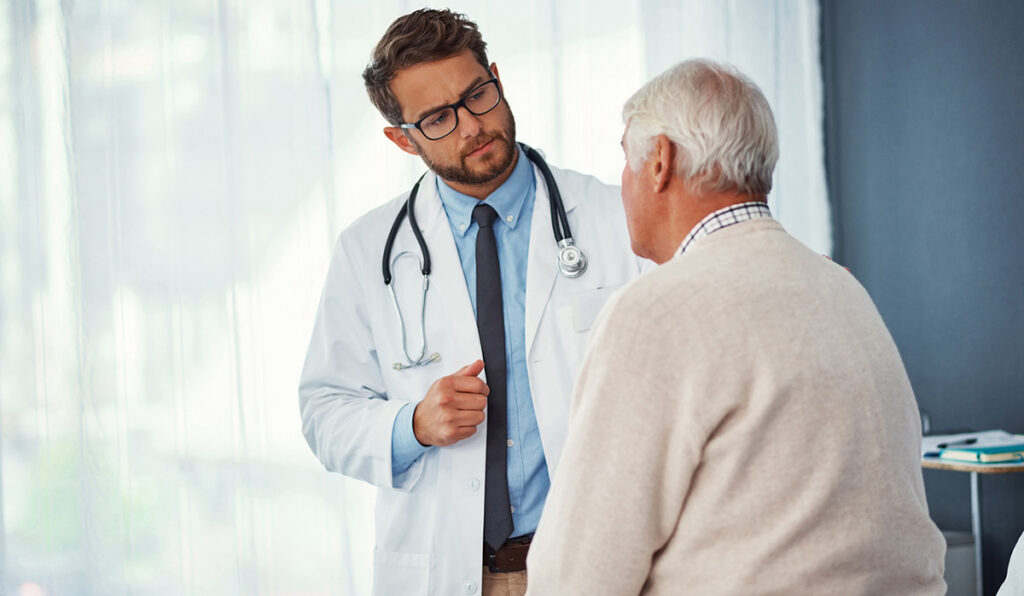 Doctor explaining mesothelioma causes and treatment options to an older patient during a consultation