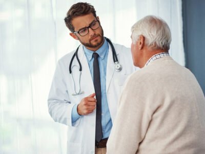 Doctor explaining mesothelioma causes and treatment options to an older patient during a consultation